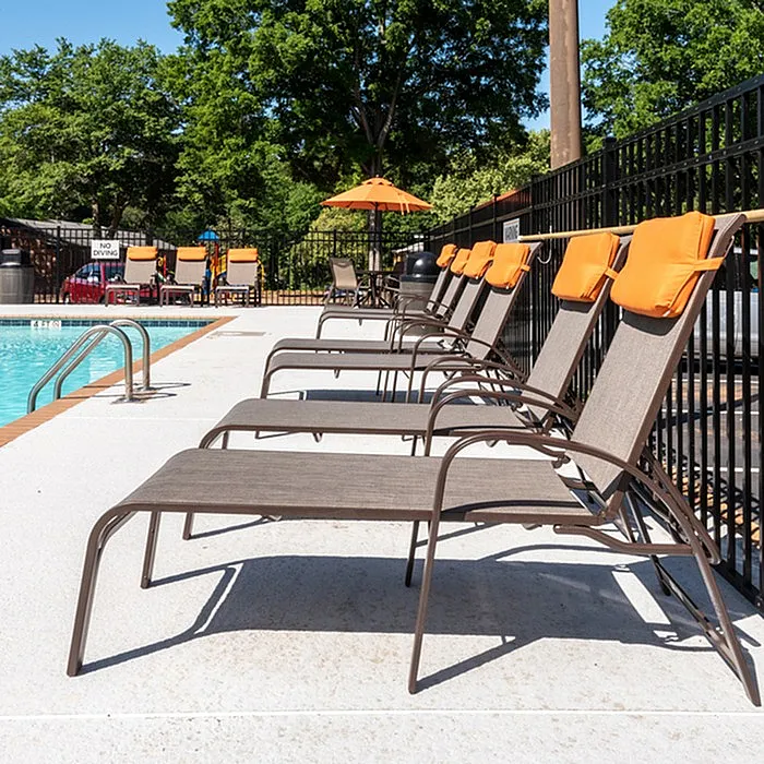 Inviting outdoor pool area with sun loungers and vibrant orange accents, perfect for relaxation.