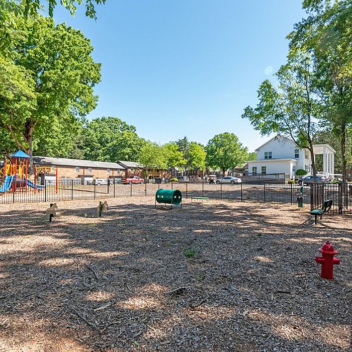 Inviting playground within a lush community setting, featuring play equipment under clear blue skies.