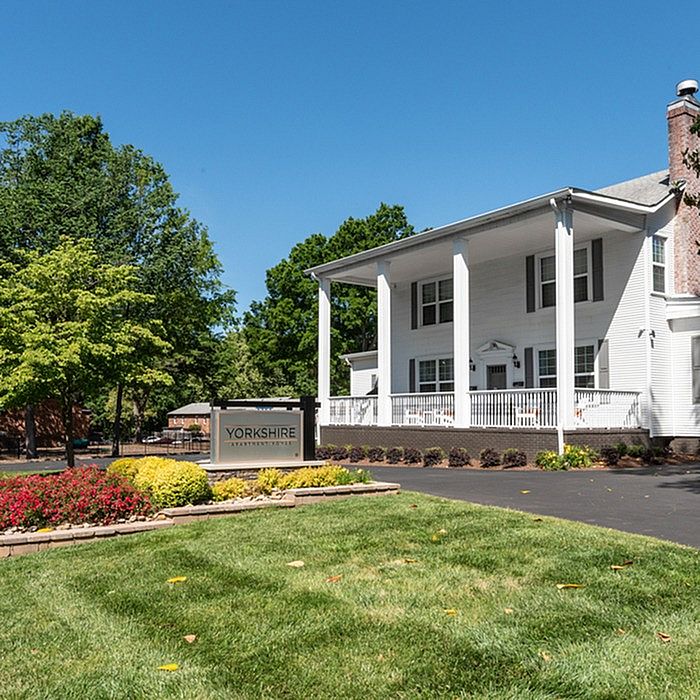 Inviting view of Yorkshire Apartments with a grand white facade, surrounded by lush greenery and vibrant flowers.