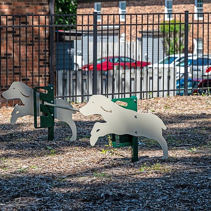 Playful dog-shaped playground equipment in a fenced outdoor area.