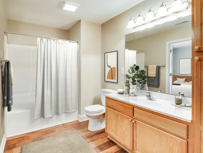 Bright and modern bathroom with wood cabinets and a large mirror.
