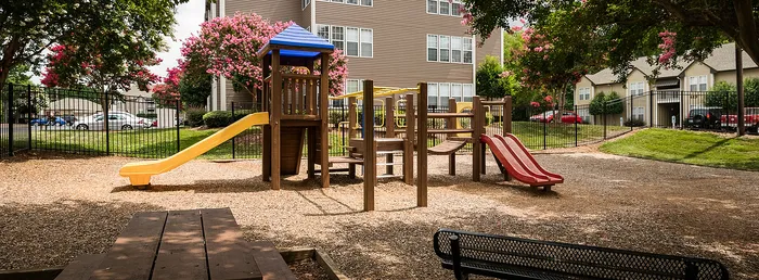Charming playground with colorful slides and climbing structures surrounded by lush greenery, ideal for family living.
