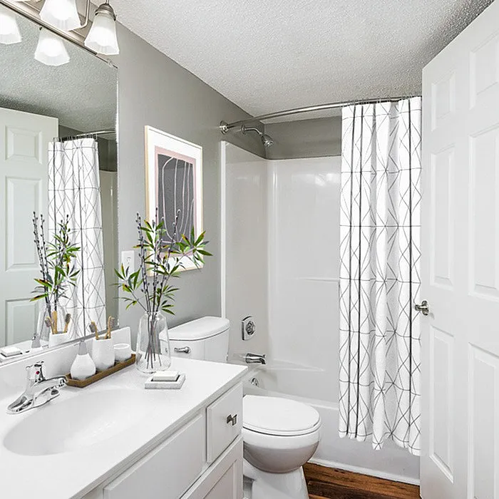 Contemporary bathroom with elegant vanity featuring a chic plant arrangement, modern fixtures, and stylish shower curtain.