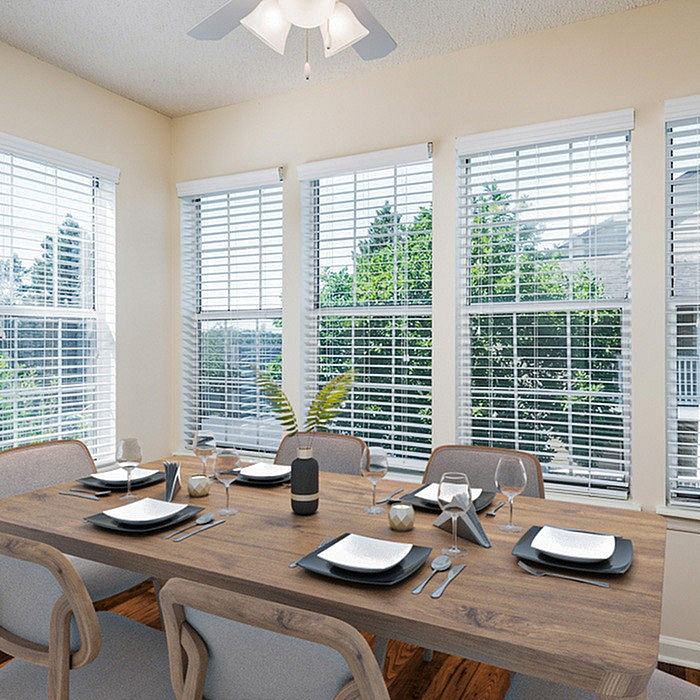 Bright and inviting dining area with elegant table setting, surrounded by large windows offering a scenic view and abundant natural light.