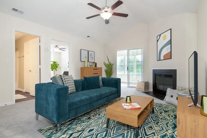 Inviting living room with vibrant teal sofa, modern art, and cozy fireplace, perfect for relaxation and entertaining.