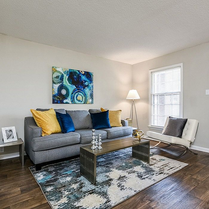 Inviting living room with modern decor, featuring a plush gray sofa, vibrant blue and yellow pillows, elegant artwork, and a stylish floor lamp.