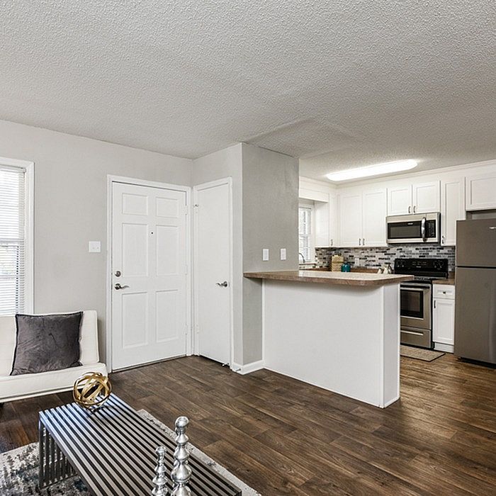 Modern apartment interior with sleek kitchen, inviting open-plan living area, and elegant wooden flooring.