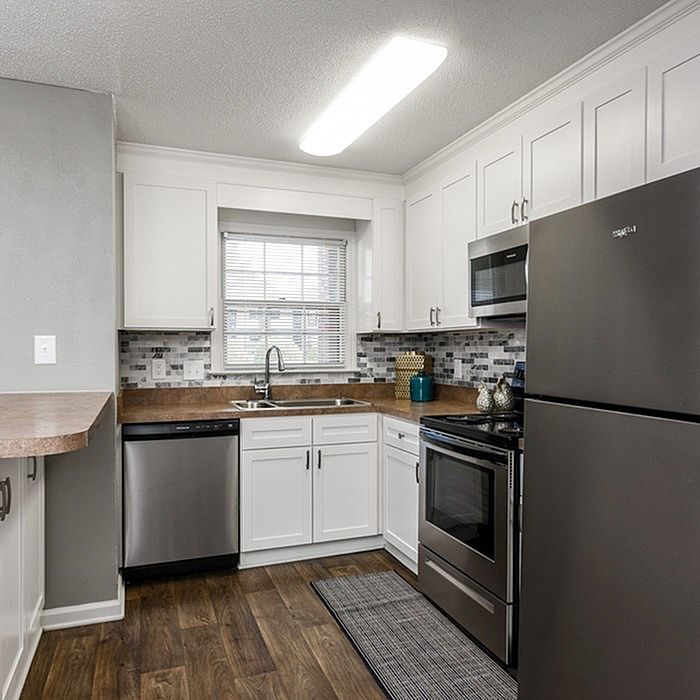 Modern kitchen with sleek stainless steel appliances, white cabinetry, and elegant tiled backsplash.