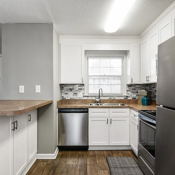 Bright and modern kitchen with sleek stainless steel appliances, elegant white cabinets, and a stylish tile backsplash.