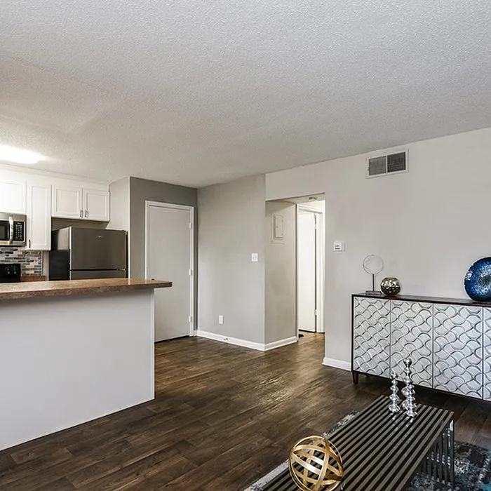 Modern open-concept living area with stylish decor and dark wood flooring, featuring a sleek kitchen with stainless steel appliances and elegant cabinetry.