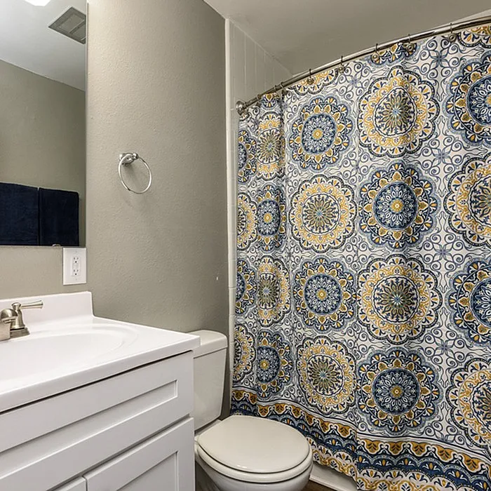 Chic bathroom with a stylish vanity and vibrant patterned shower curtain, offering a modern and inviting touch.