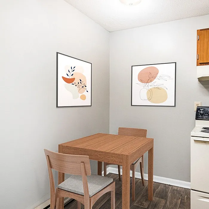 Charming dining corner with modern art, wooden table, and cozy chairs, perfect for intimate meals.