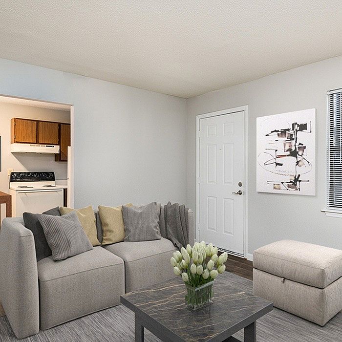 Inviting living room with stylish gray sofa, chic marble coffee table, modern art, and cozy open kitchen.