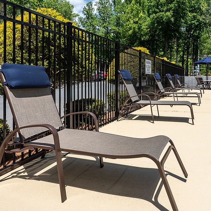 Sunny outdoor lounge area with stylish sunbeds and lush green surroundings, perfect for relaxation.