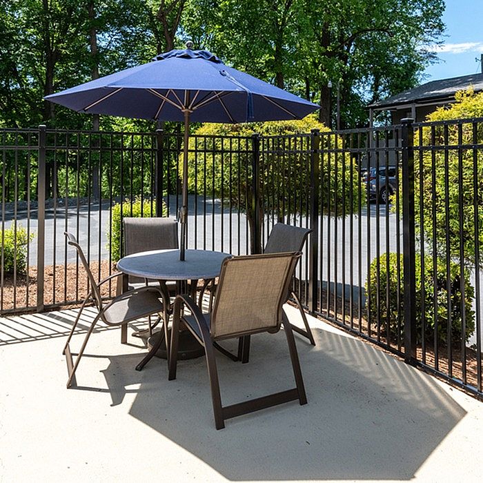 Charming outdoor patio with elegant seating set and vibrant blue umbrella, perfect for relaxing and entertaining.