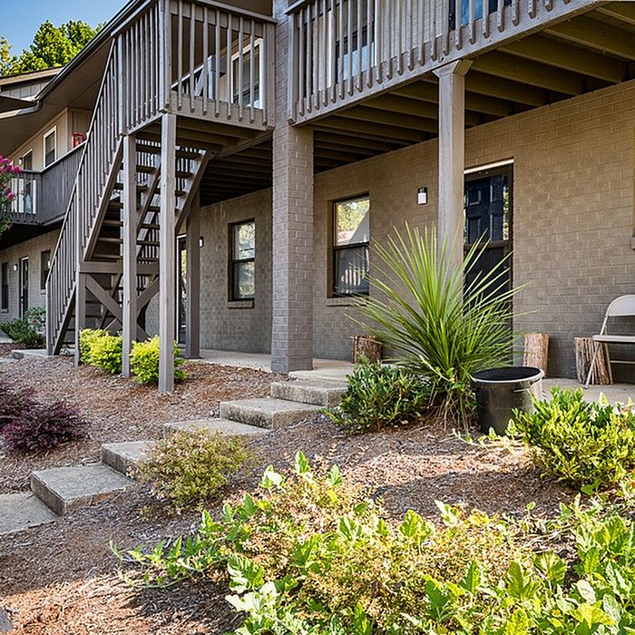 Charming apartment exterior with garden landscaping and elevated balcony, ideal for outdoor relaxation.