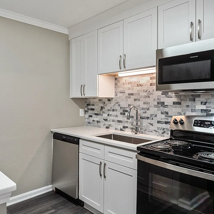 Modern kitchen with sleek stainless steel appliances, elegant white cabinetry, and a stylish tile backsplash.