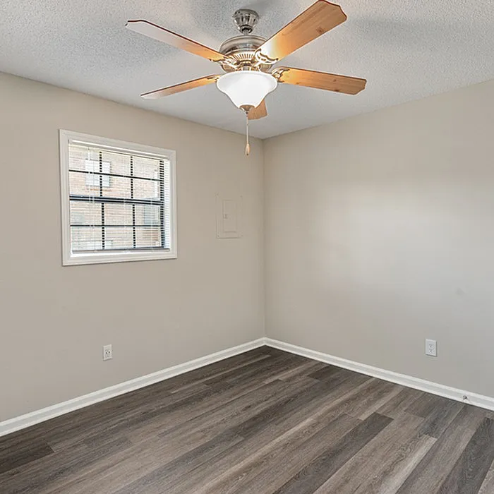 Bright and inviting room with elegant hardwood flooring and a chic ceiling fan, perfect for relaxation or work.