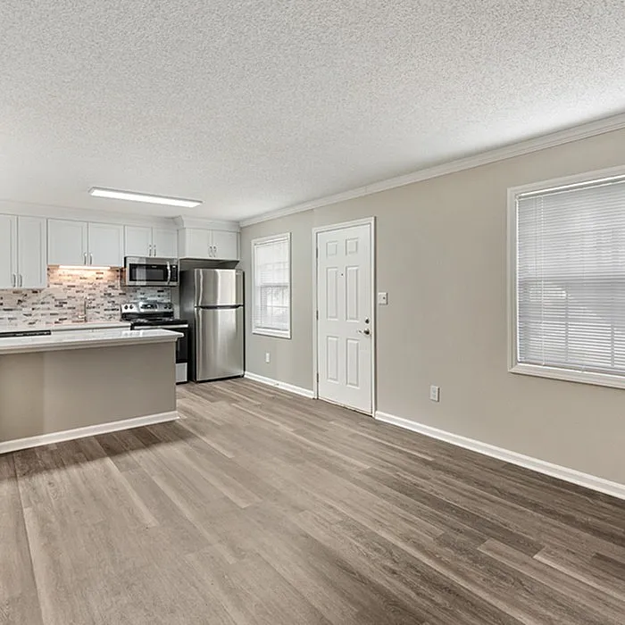 Modern open-concept kitchen with sleek stainless steel appliances, chic backsplash, and elegant hardwood flooring, flooded with natural light.