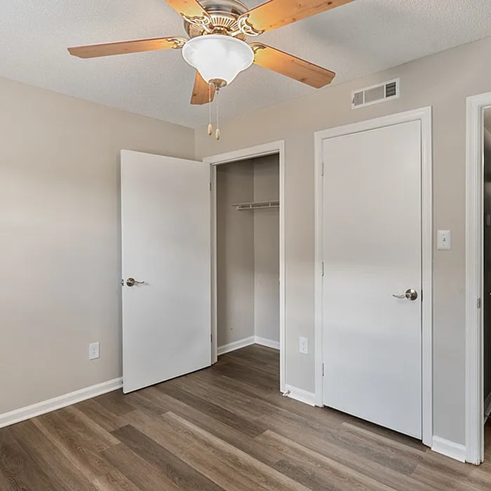 Bright bedroom space featuring elegant wooden flooring, modern ceiling fan, and a spacious closet.