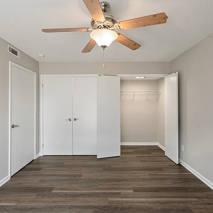 Bright and inviting bedroom with elegant ceiling fan, spacious closets, and stylish hardwood flooring.