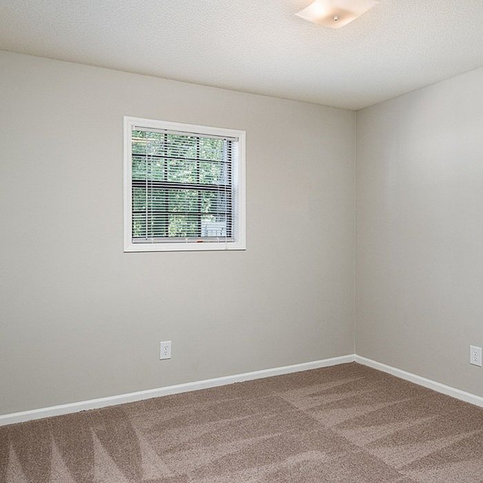 Bright and inviting bedroom with plush carpeting and a window overlooking lush greenery.