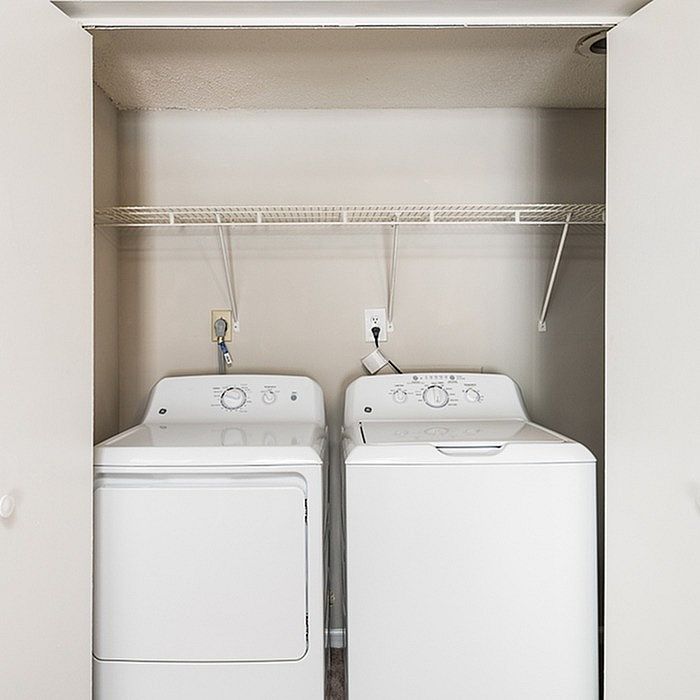 Modern laundry nook featuring sleek washer and dryer with convenient overhead shelving.