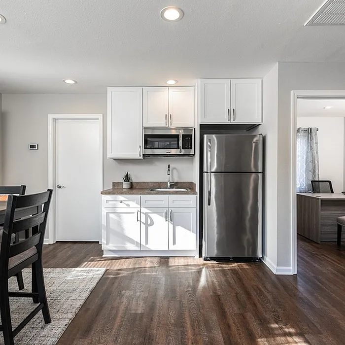 Contemporary kitchen with sleek stainless steel appliances, elegant white cabinetry, and rich wood flooring for a modern touch.