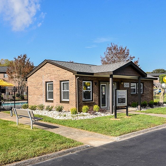 Charming brick office building surrounded by lush greenery and a vibrant pool area, ideal for community living.
