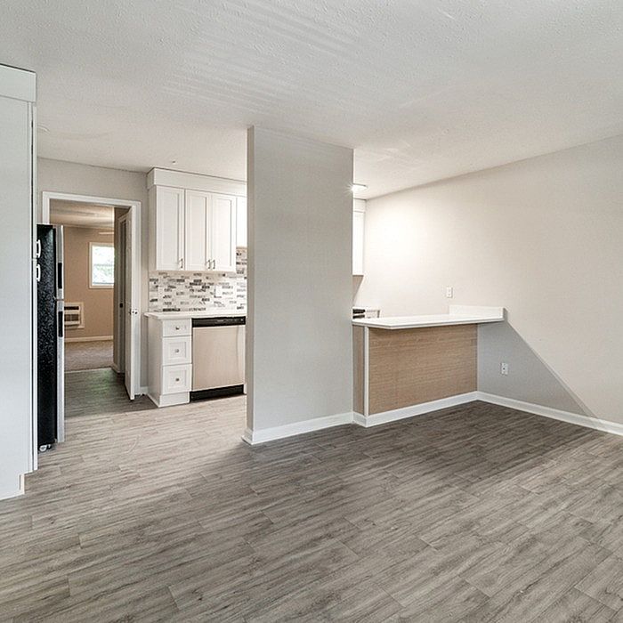 Chic open-plan apartment with elegant wood flooring, modern kitchen with stylish cabinetry, and inviting natural light.