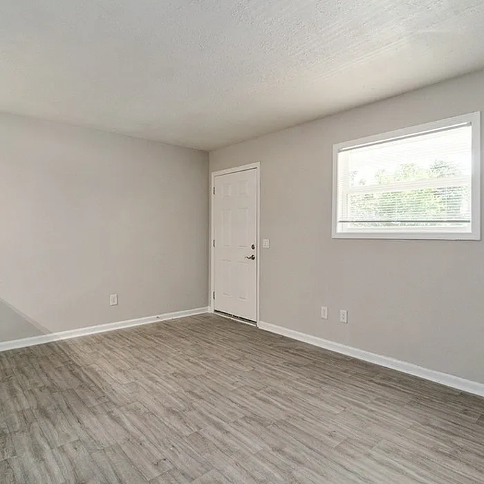 Bright and spacious room with modern wood flooring and abundant natural light, perfect for a cozy and stylish living space.