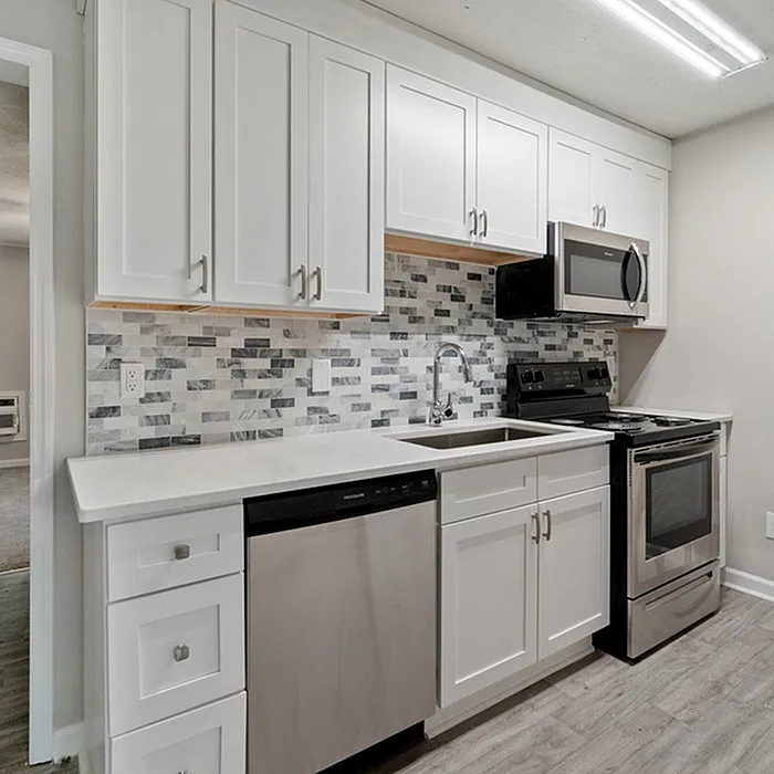 Modern kitchen with sleek white cabinetry, stainless steel appliances, and stylish tiled backsplash for a contemporary look.