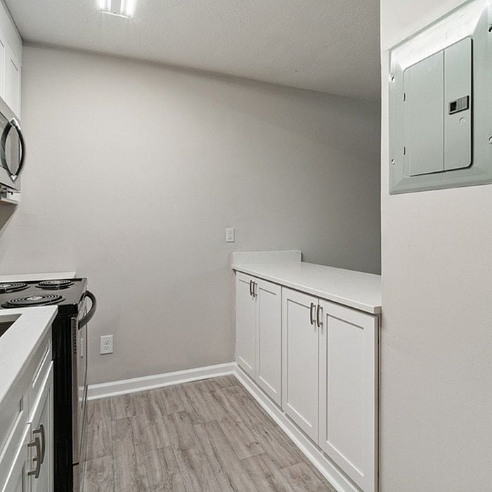 Modern kitchen featuring sleek white cabinetry, stainless steel appliances, and elegant laminate flooring.