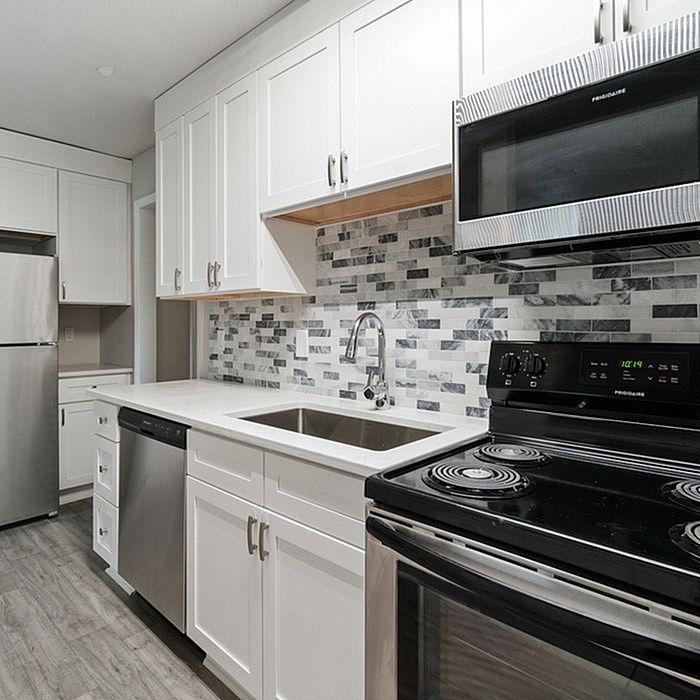 Modern kitchen with sleek stainless steel appliances, elegant white cabinetry, and stylish mosaic backsplash tiles.