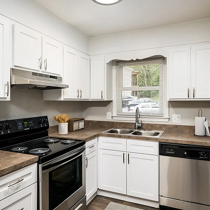 Modern kitchen with sleek white cabinetry, stainless steel appliances, and a charming window view.