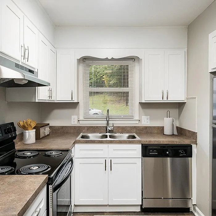Charming kitchen with elegant white cabinetry, modern appliances, and a sunlit window.