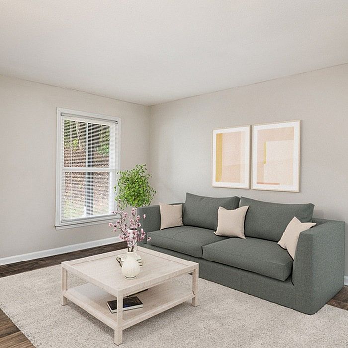 Inviting living room with elegant gray sofa, chic coffee table, and natural light streaming through modern window.