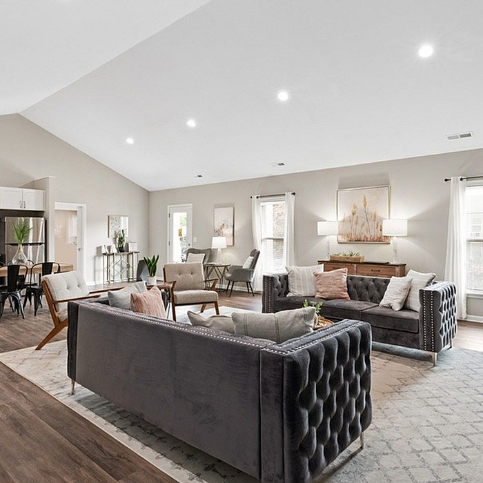 Elegant open-concept living room with plush velvet sofas, stylish decor, and abundant natural light creating a welcoming ambiance.