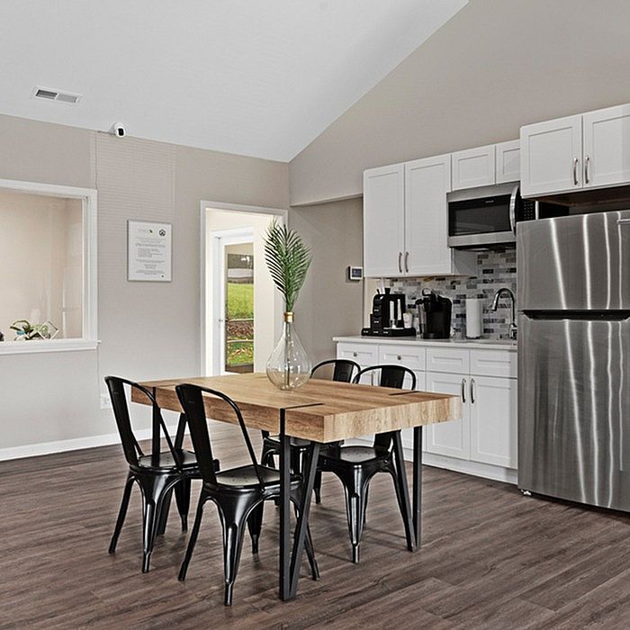 Modern kitchen and dining area with sleek stainless steel appliances, chic wooden dining table, and elegant cabinetry, perfect for stylish living.