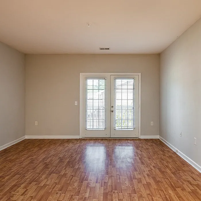 Bright and airy room with elegant wood flooring, inviting natural light through large French doors, perfect for a cozy living space.