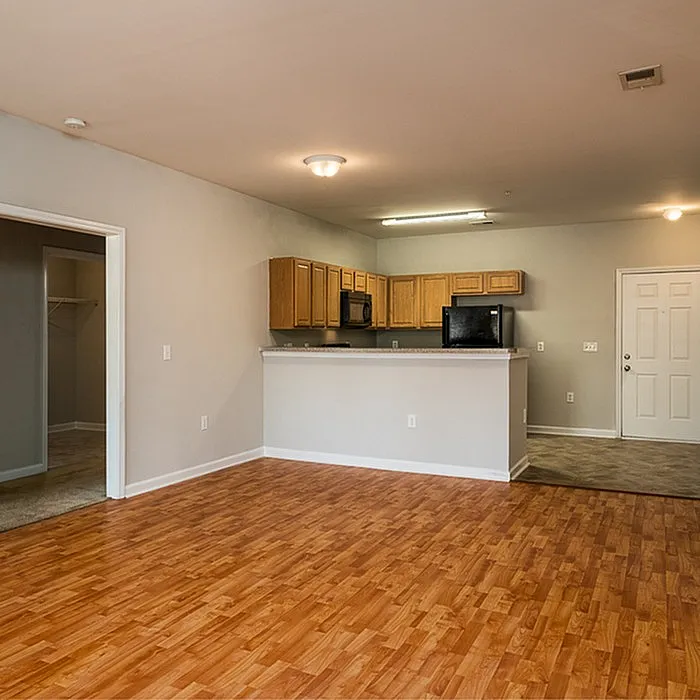 Inviting open-concept living space with elegant wooden floors and a modern kitchen featuring sleek appliances and ample cabinetry.