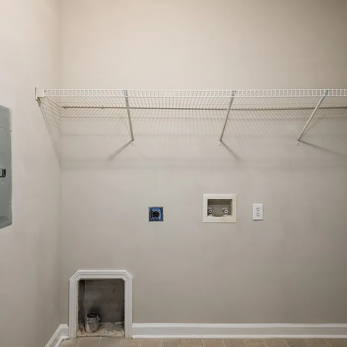 Spacious laundry room with convenient shelving and utility connections, ready for appliance installation.