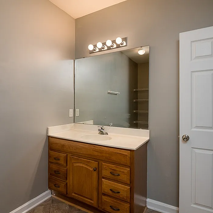 Modern bathroom with elegant wooden vanity, large mirror, and soft, warm lighting.