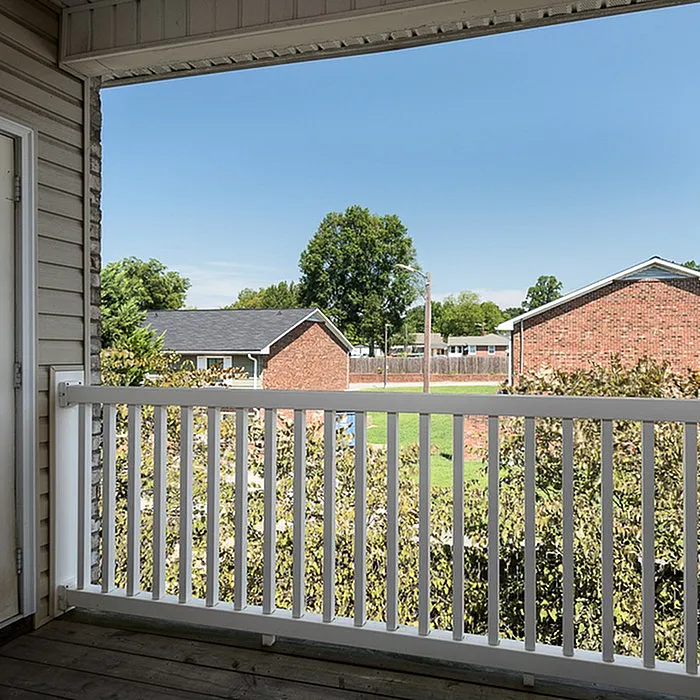 Charming balcony view showcasing lush greenery and appealing brick architecture, perfect for enjoying serene outdoor moments.