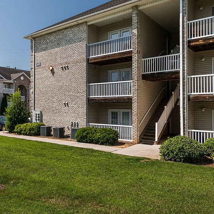 Charming apartment building with balconies and lush green landscaping, offering a welcoming and serene living environment.