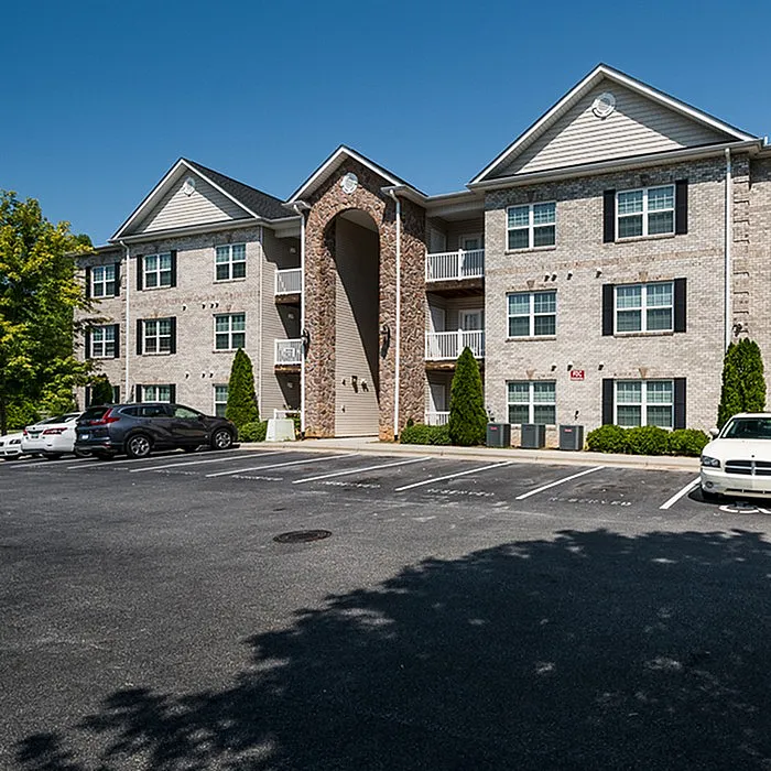 Charming brick apartment complex with modern architecture, featuring well-maintained greenery and ample parking space.