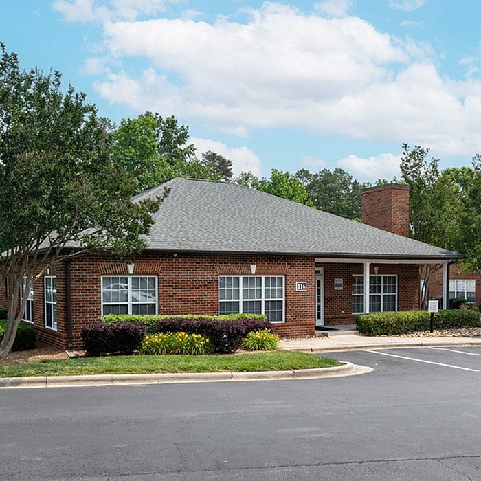 Charming brick apartment building with lush landscaping and spacious windows, nestled in a serene neighborhood setting.