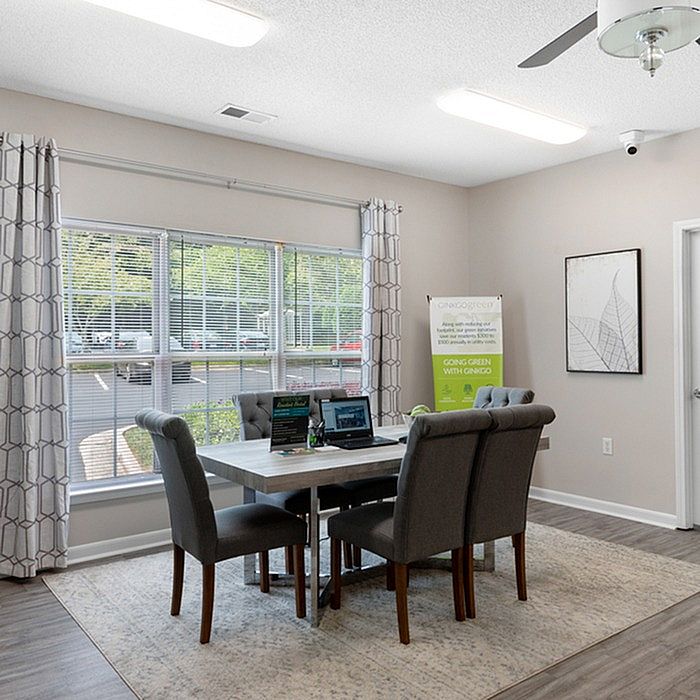 Bright office space with large windows, modern decor, and elegant gray seating arranged around a polished table, perfect for productive meetings.