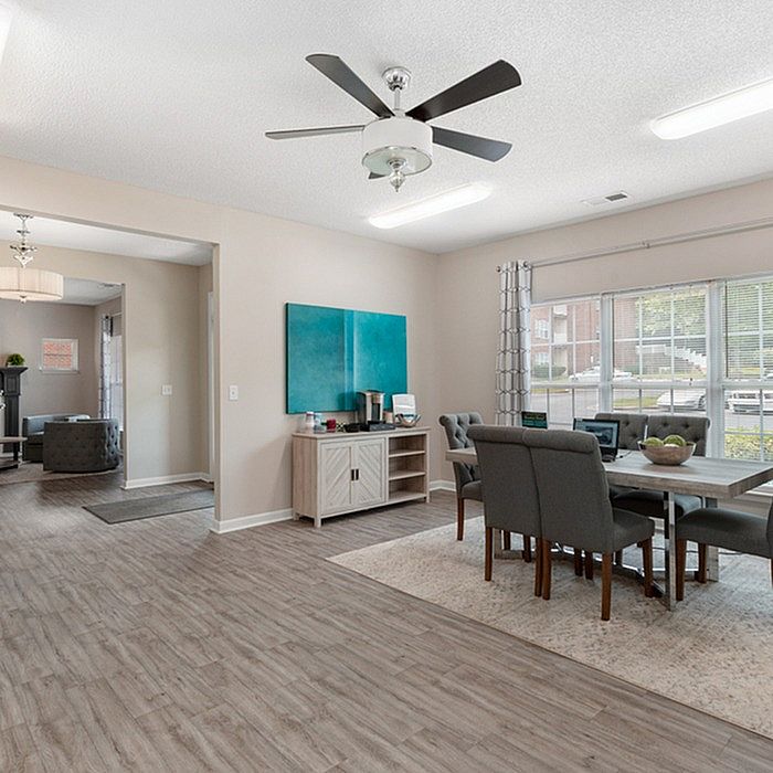 Bright and welcoming open-concept dining and living area with stylish decor, modern ceiling fan, and large sunlit windows.