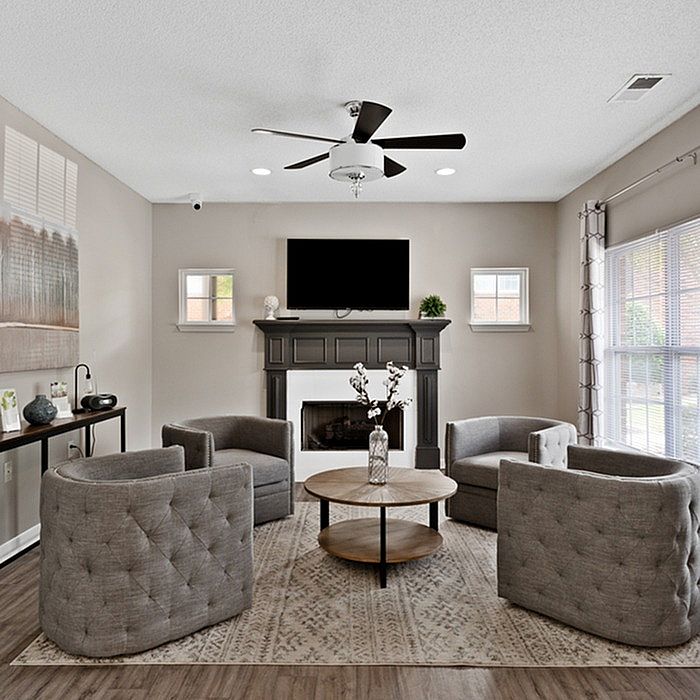 Elegant living room with a sophisticated fireplace, modern gray armchairs, and abundant natural light, perfect for cozy gatherings.